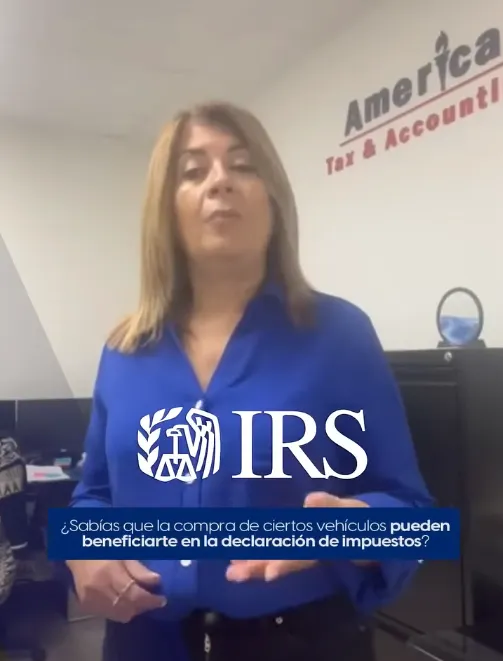 Woman standing in front of camera wearing a blue business shirt. In the background there is a white wall with the America Tax & Accounting, Corp. Logo.